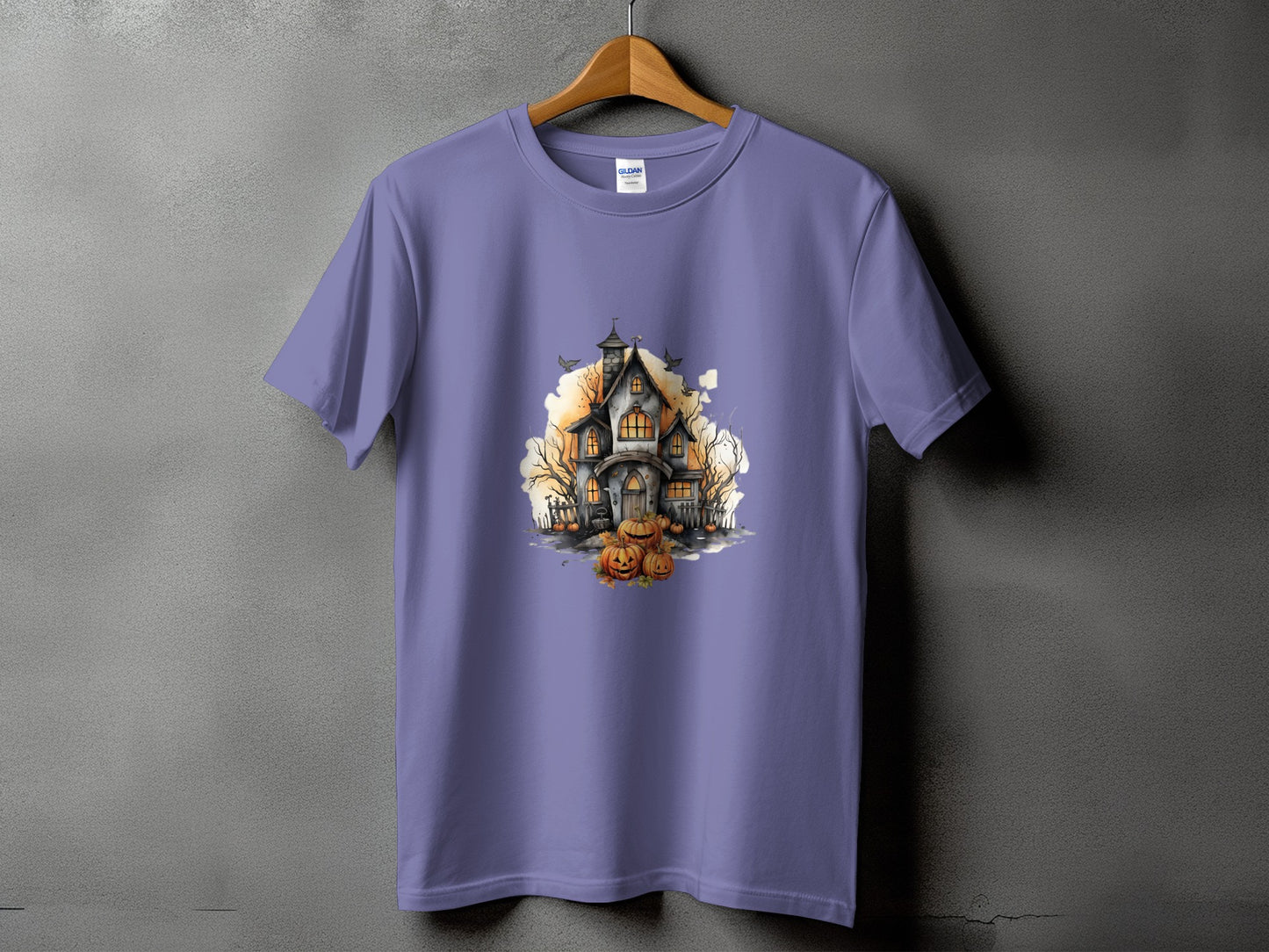 Purple t-shirt featuring a watercolor print of a haunted house and pumpkins.