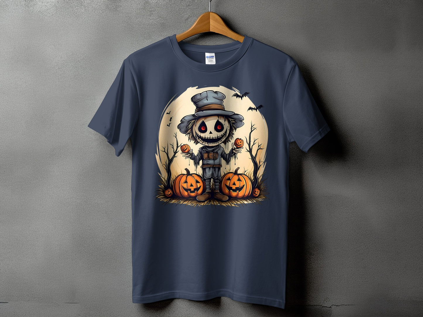 T-shirt with a cartoon scarecrow holding pumpkins against a moon backdrop.