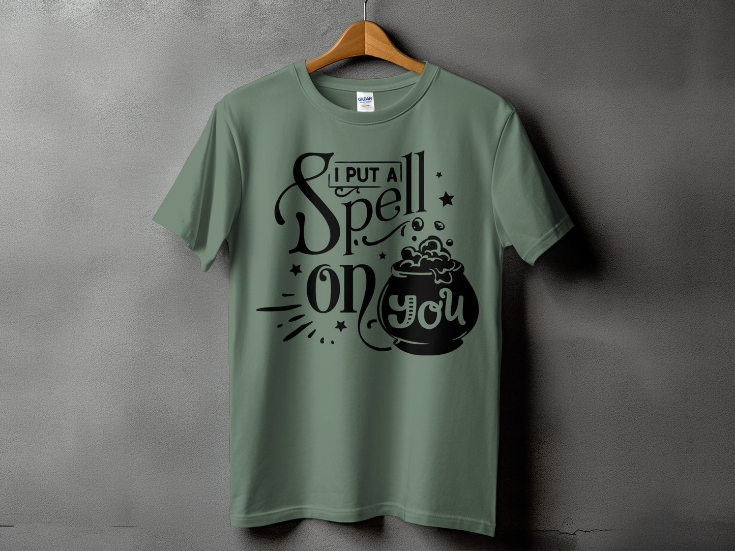 Green t-shirt with black text and cauldron graphic saying "I put a spell on you."
