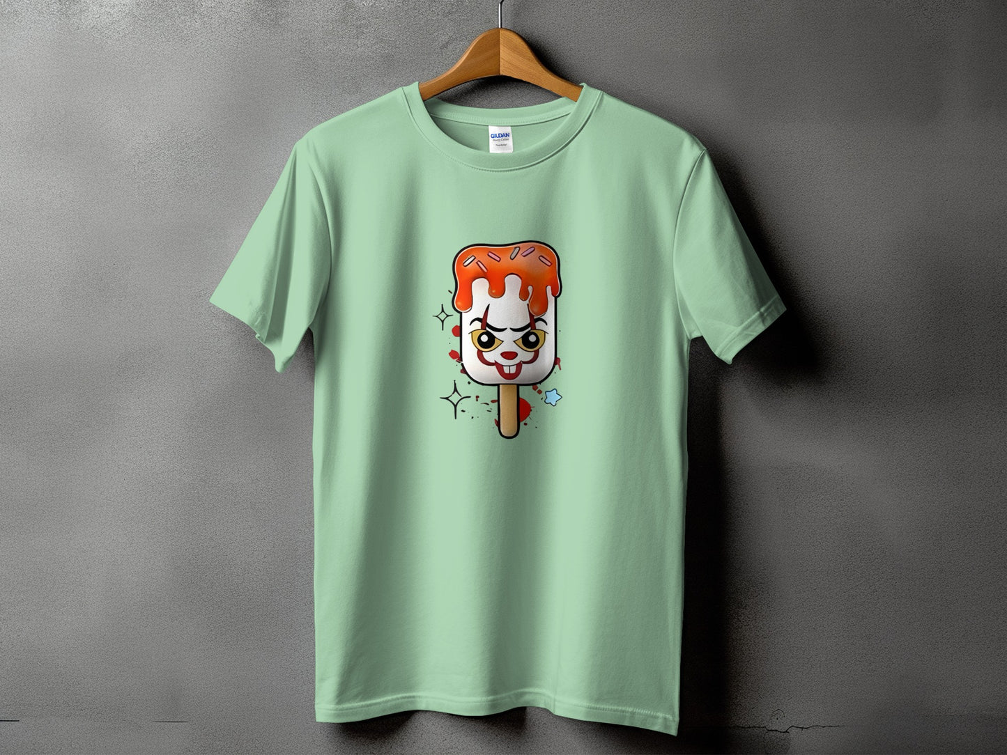 Pale green t-shirt with a cartoon ice pop featuring a clown face.
