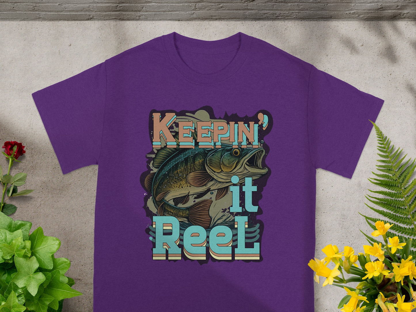Purple t-shirt with graphic of bass fish and text "Keepin' it Reel."