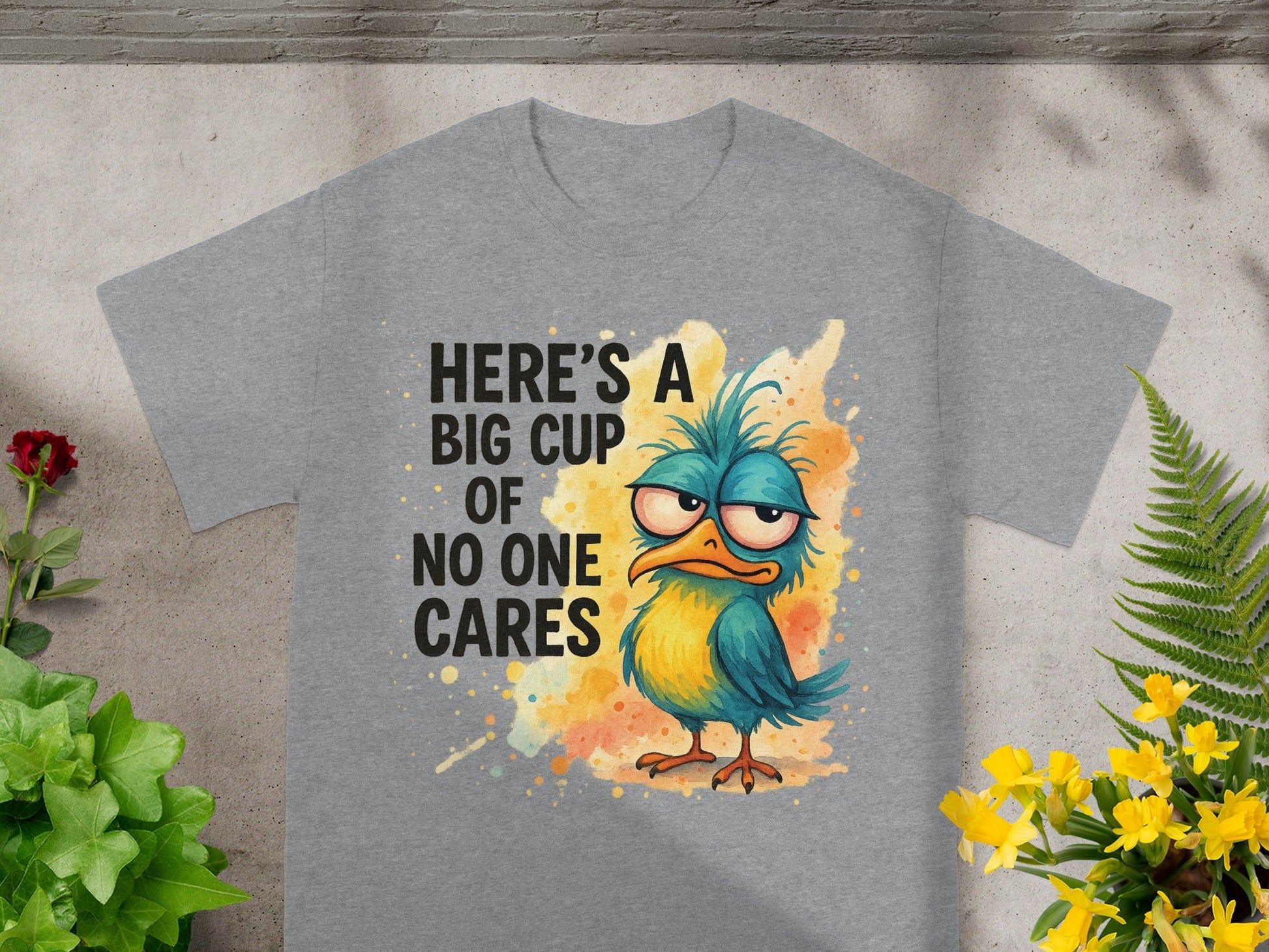 Grey t-shirt with a cartoon bird and text "HERE'S A BIG CUP OF NO ONE CARES".