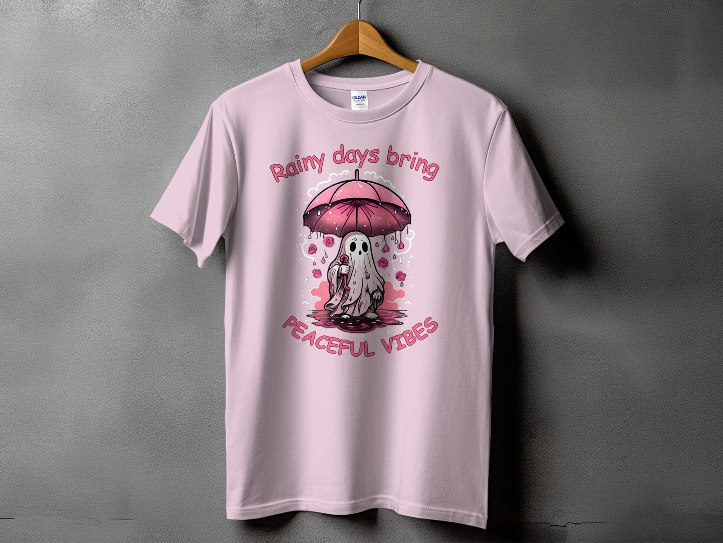 Pink t-shirt with ghost under umbrella and text "Rainy days bring peaceful vibes."