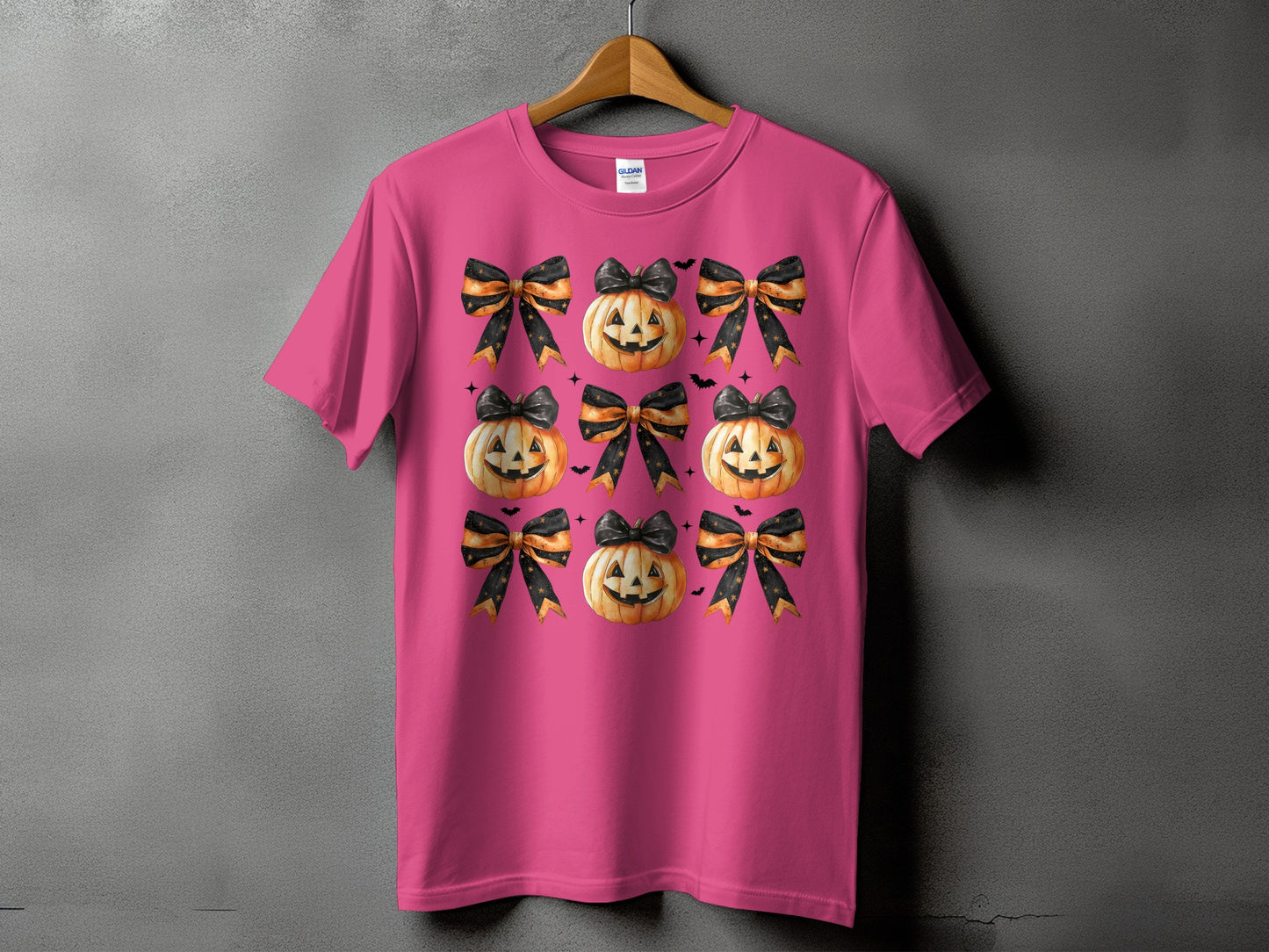 Pink t-shirt with a repeating pattern of Halloween pumpkins and black and orange bows.