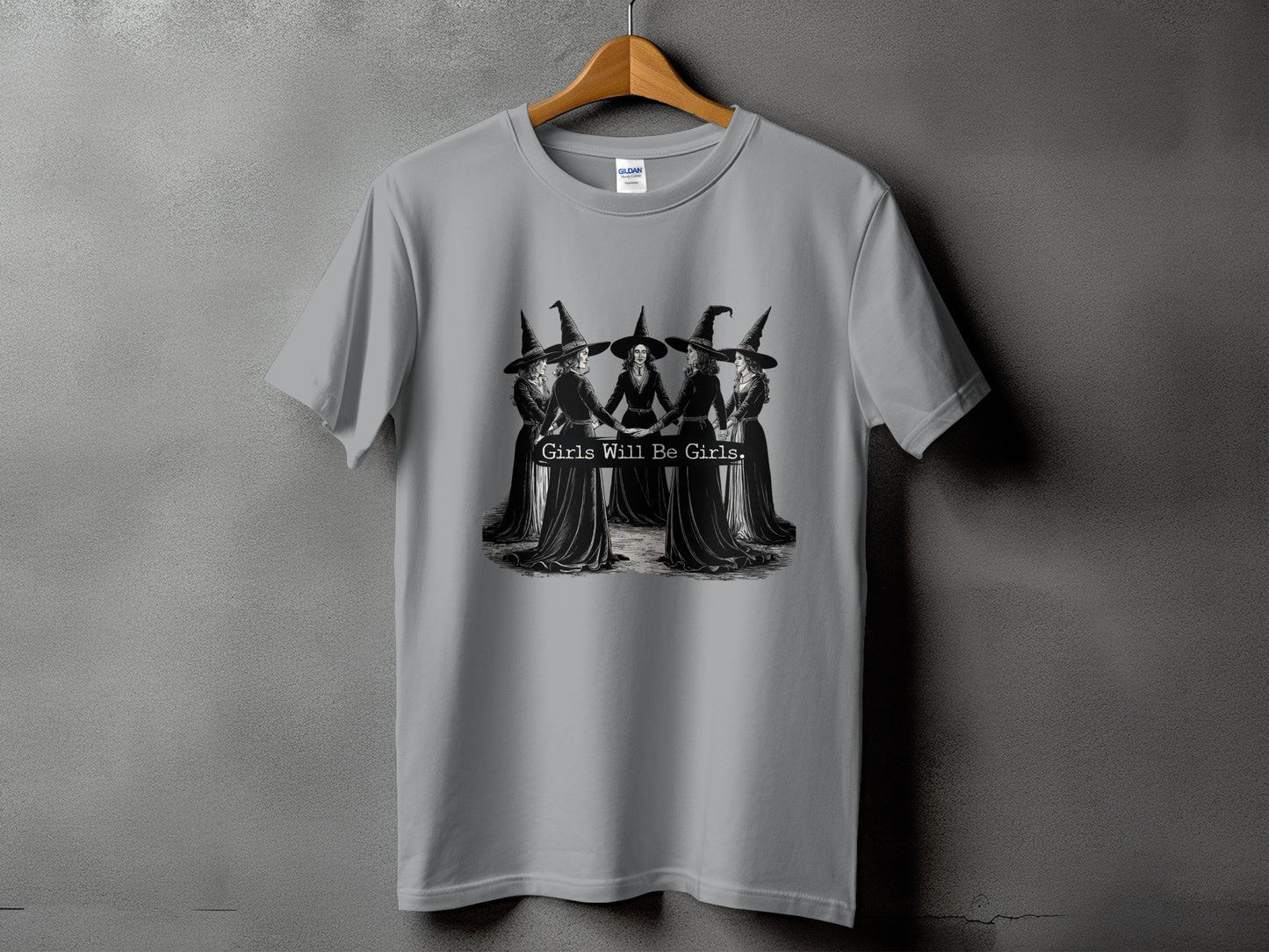 Gray t-shirt with a graphic of five witches in a circle, text reads "Girls Will Be Girls."