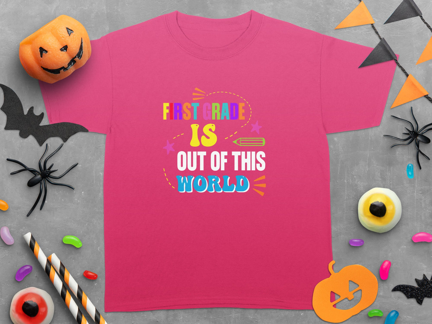 Pink t-shirt with "First Grade is Out of This World" text, accented by Halloween decorations.