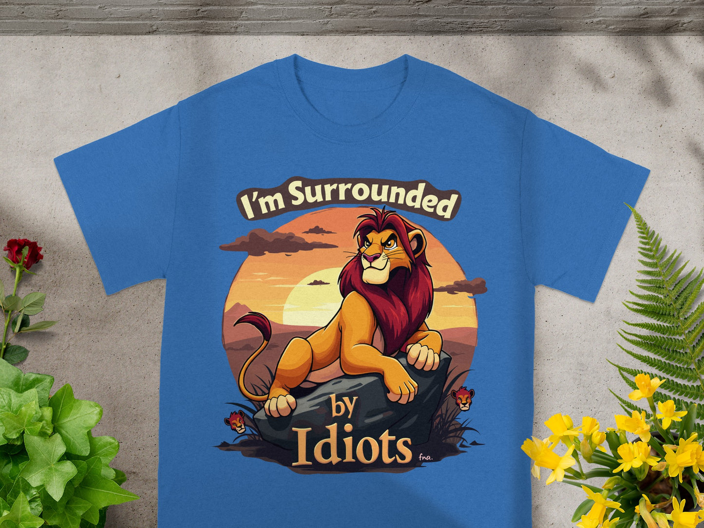 Blue t-shirt with "I'm Surrounded by Idiots" text and lion graphic.