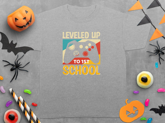 Grey t-shirt with "LEVELED UP TO 1ST SCHOOL" and a video game controller graphic.