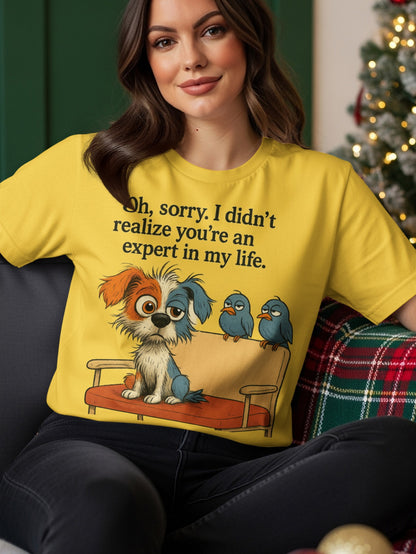 Yellow t-shirt with graphic of a dog and two birds on a couch, text reads "Oh, sorry. I didn't realize you're an expert in my life."