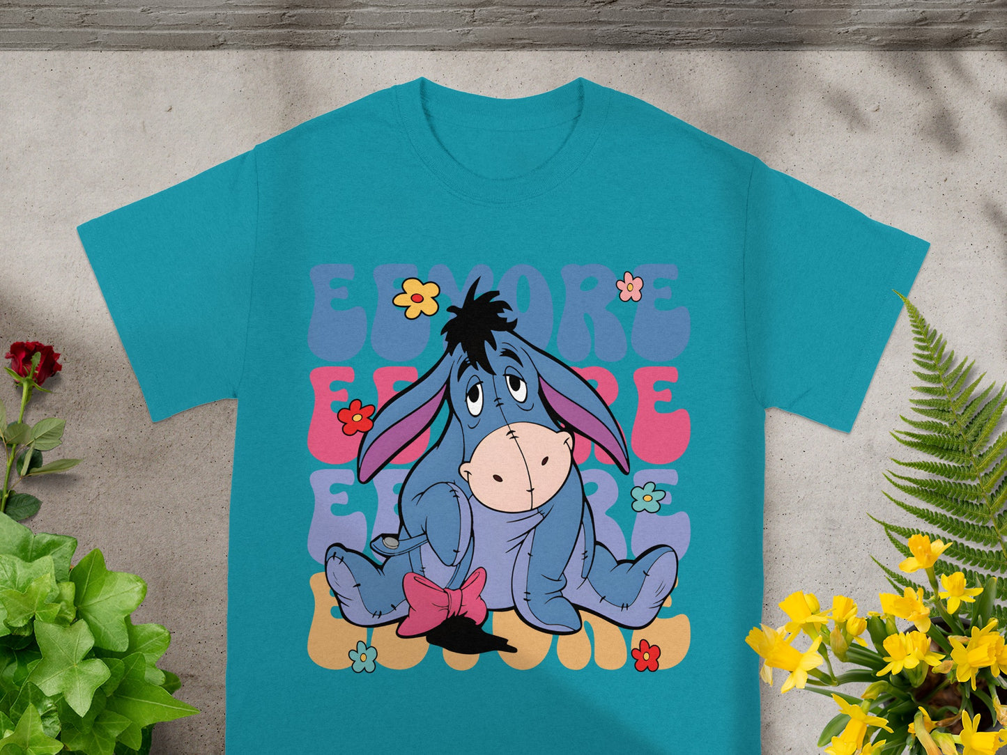 Eeyore graphic on a teal t-shirt with "Eeyore" text and flowers.