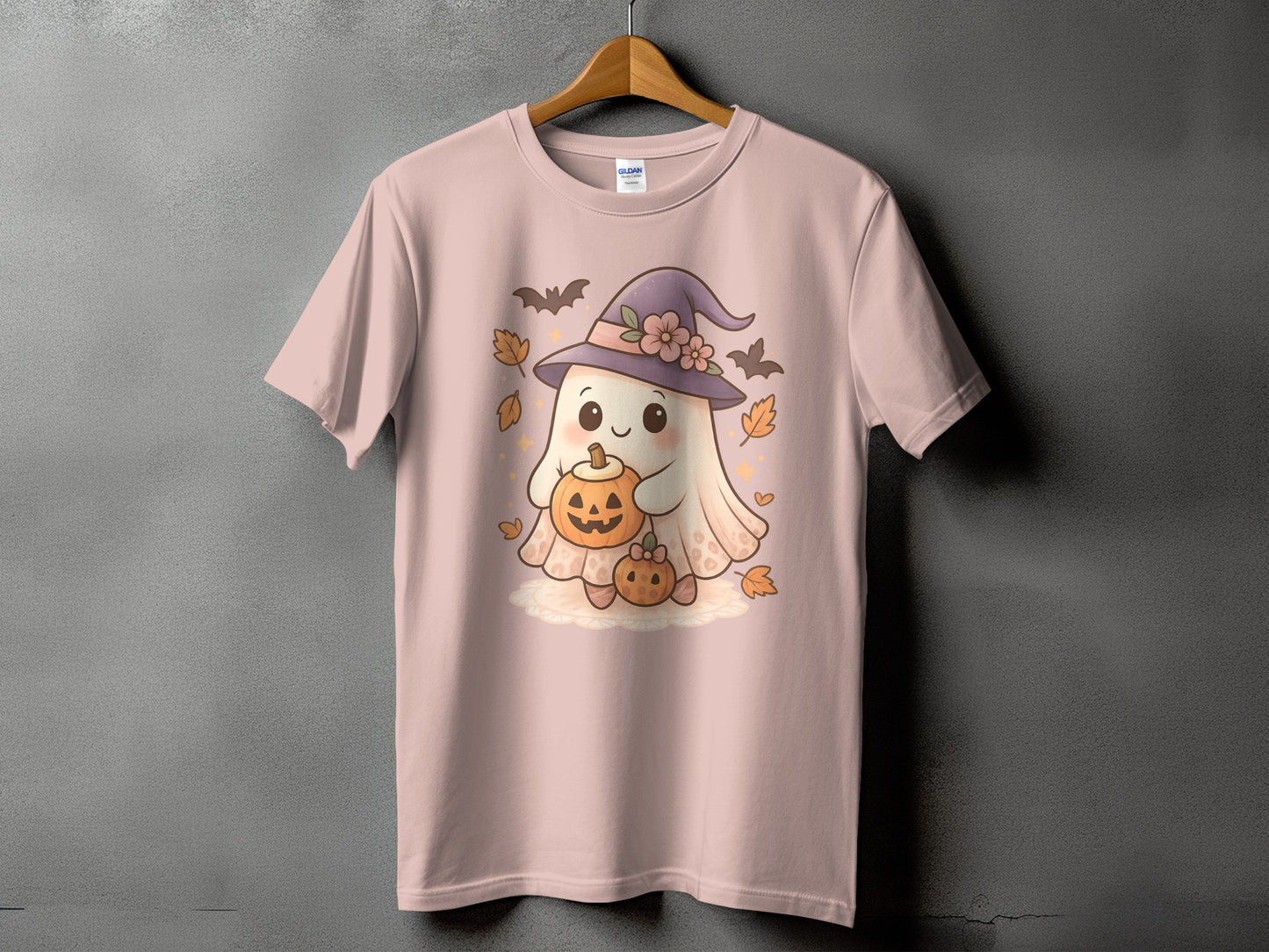 Ghost with pumpkins, witch hat, bats, and leaves on a pink t-shirt.