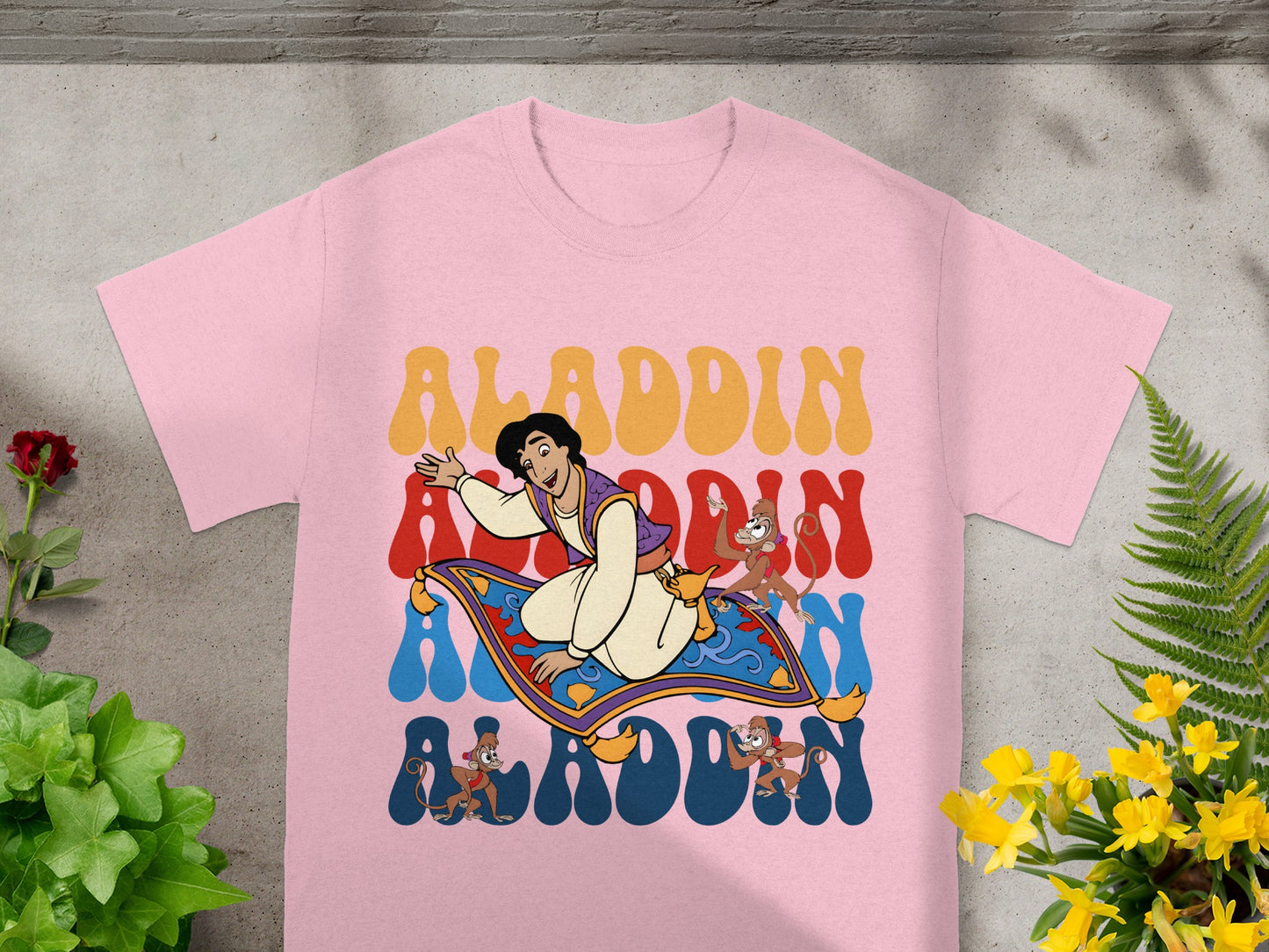 Aladdin, Abu, and magic carpet graphic on a pink t-shirt.