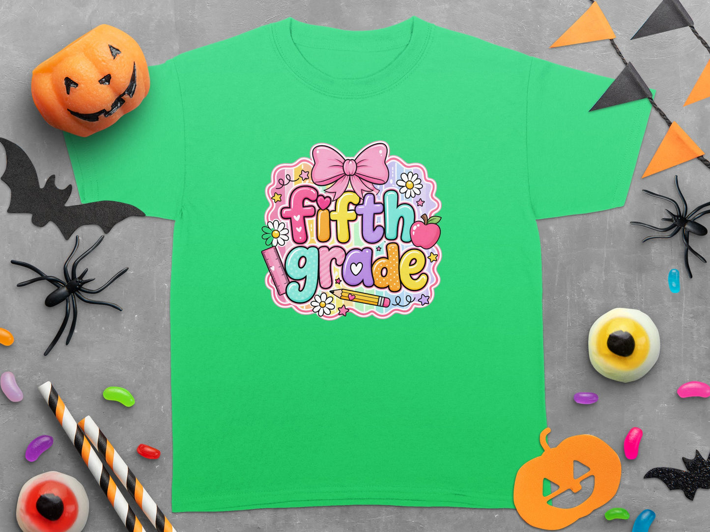 Green t-shirt with "fifth grade" graphic featuring a pink bow and classroom items.