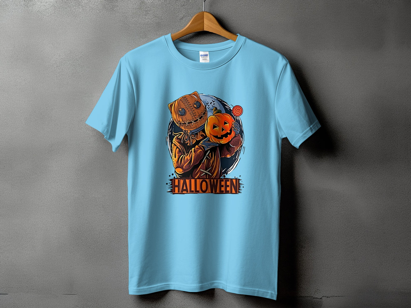 Light blue t-shirt with a burlap-headed scarecrow holding a pumpkin and lollipop.