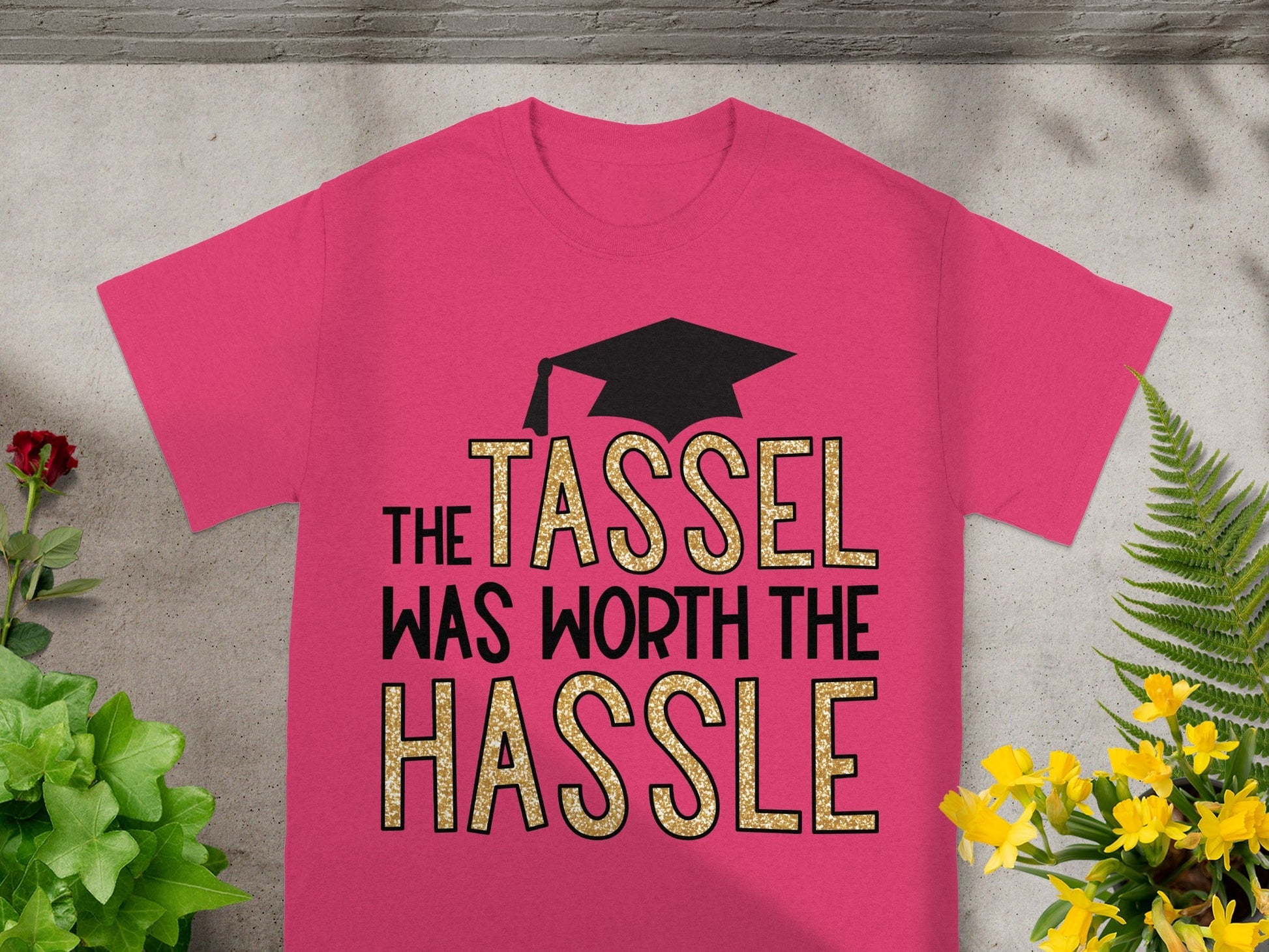 Pink t-shirt with "THE TASSEL WAS WORTH THE HASSLE" in glitter lettering.