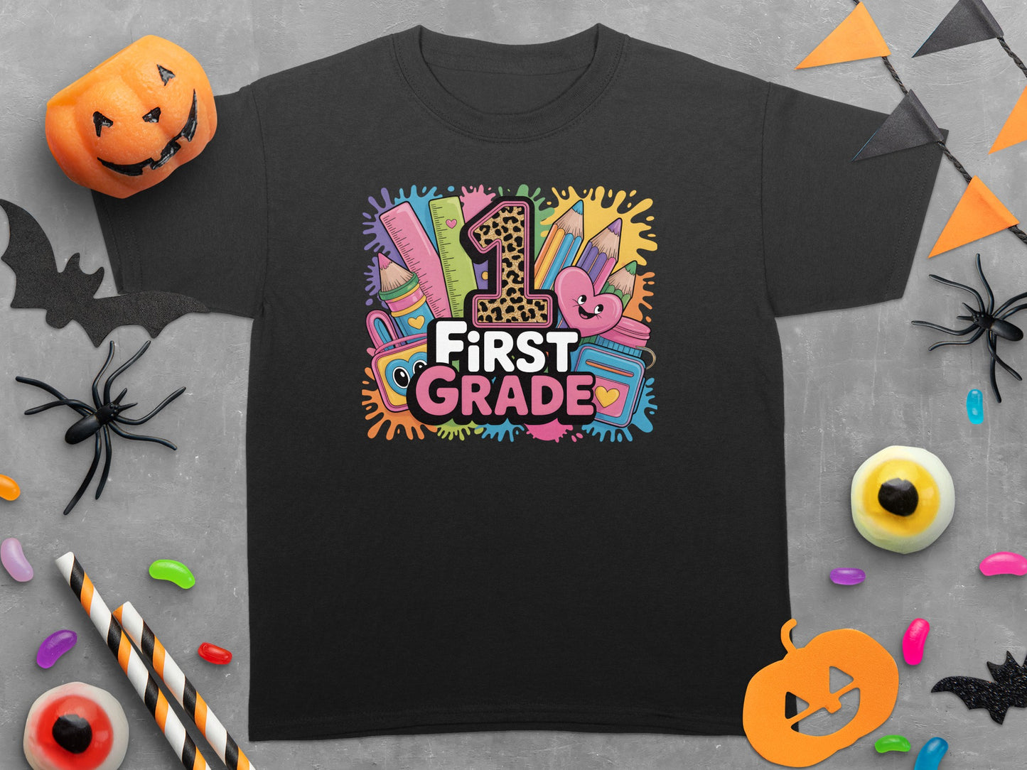 Black t-shirt with "First Grade" text surrounded by colorful school supplies and playful graphics.