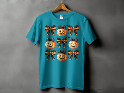 Teal t-shirt with a repeating pattern of smiling jack-o'-lanterns and black and orange bows.