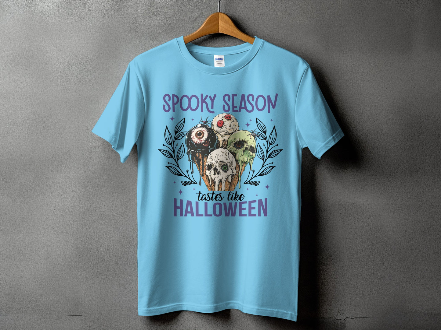 Light blue t-shirt with "Spooky Season tastes like Halloween" text and spooky ice cream cone graphic.