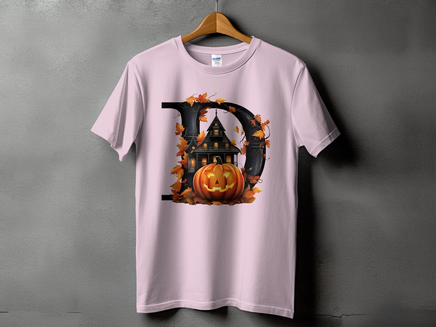 Pink t-shirt with a large letter D graphic featuring a haunted house and pumpkin.
