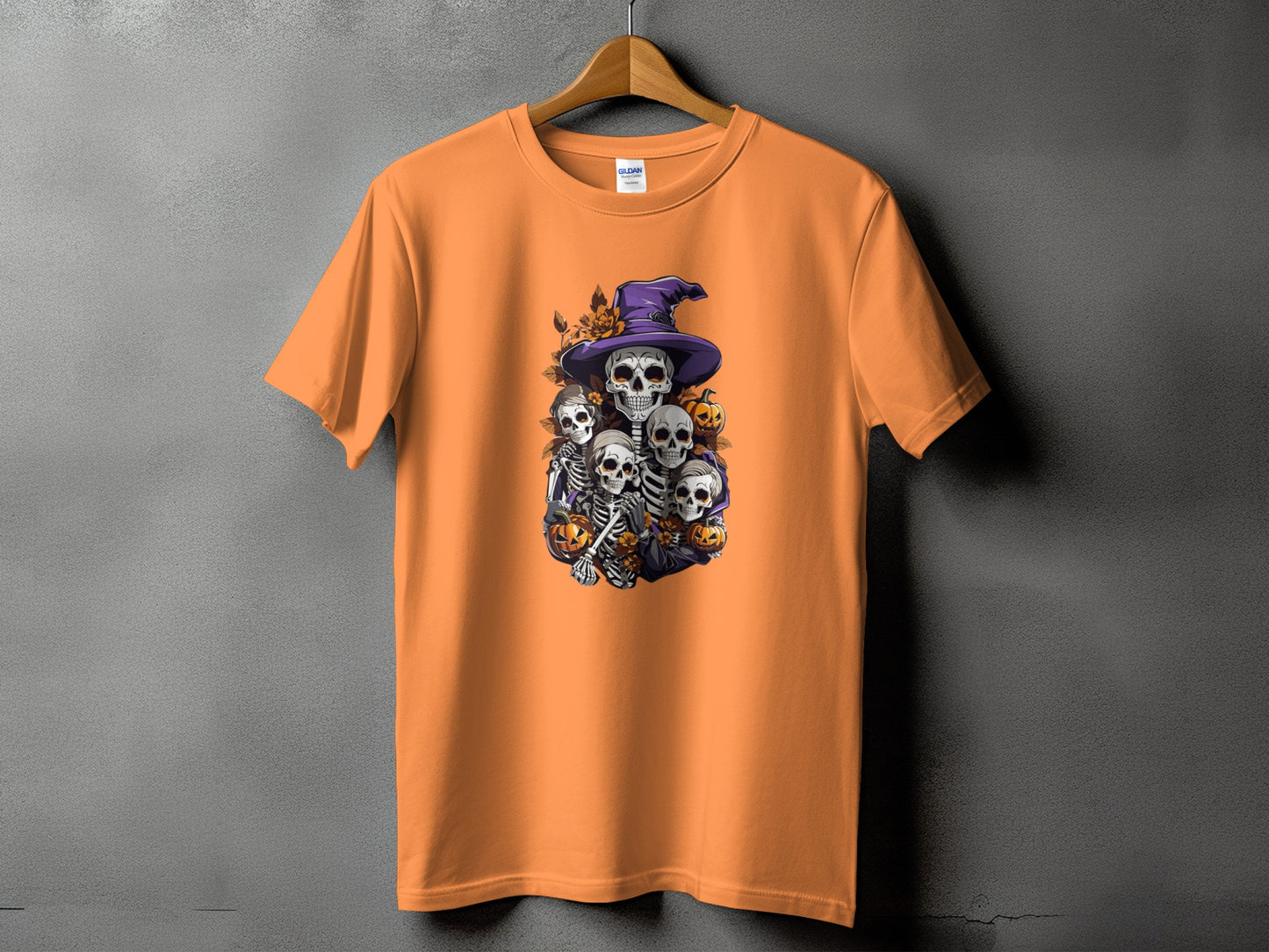 Orange t-shirt with a Halloween graphic of skeletons, pumpkins, and a witch hat.