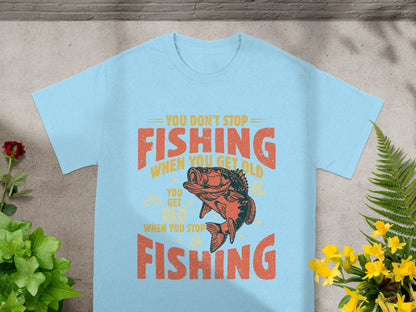 Light blue t-shirt with orange and yellow text reading "You Don't Stop Fishing When You Get Old, You Get Old When You Stop Fishing" and a fish graphic.