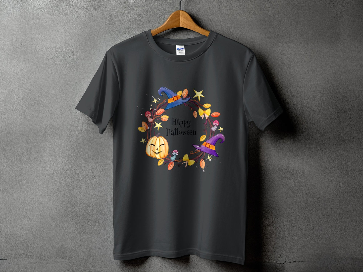 Dark gray t-shirt with a Halloween wreath design featuring a pumpkin, witch hats, leaves, and mushrooms.