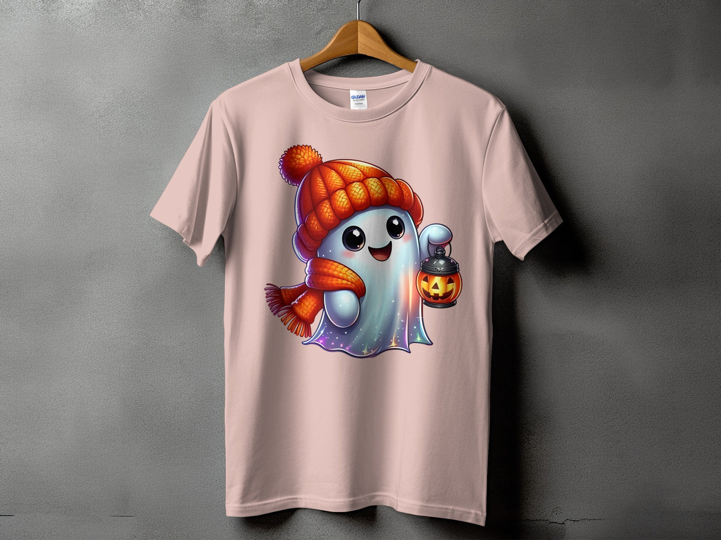 Ghost wearing a winter hat and scarf holds a pumpkin lantern on a pink t-shirt.