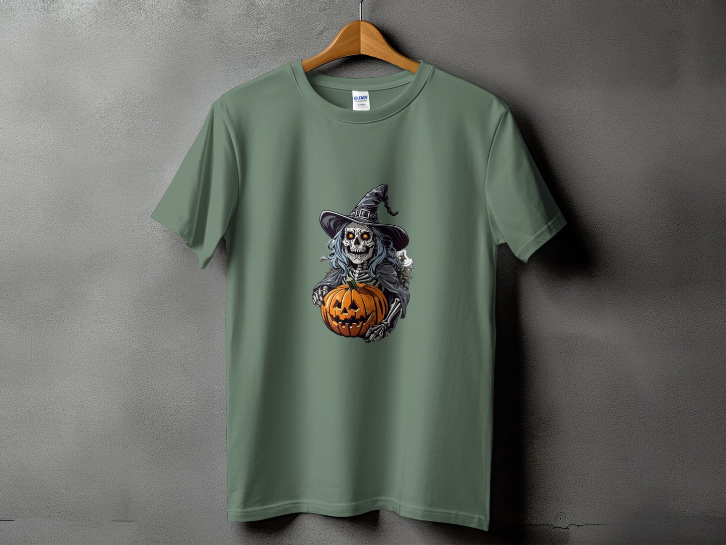 Skeleton witch holding a jack-o'-lantern on a green t-shirt.