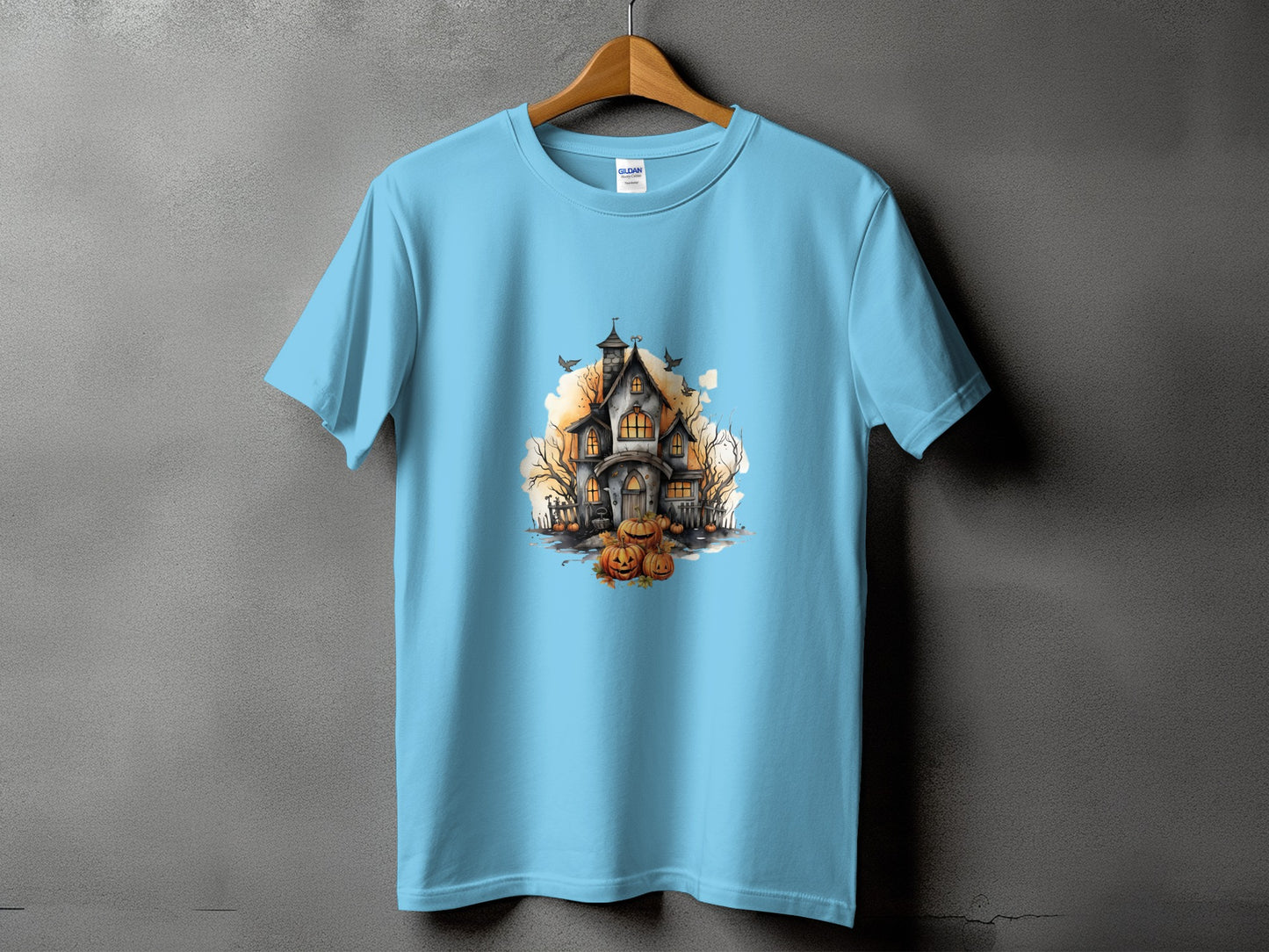 Light blue t-shirt with a watercolor print of a haunted house, pumpkins, and bats.