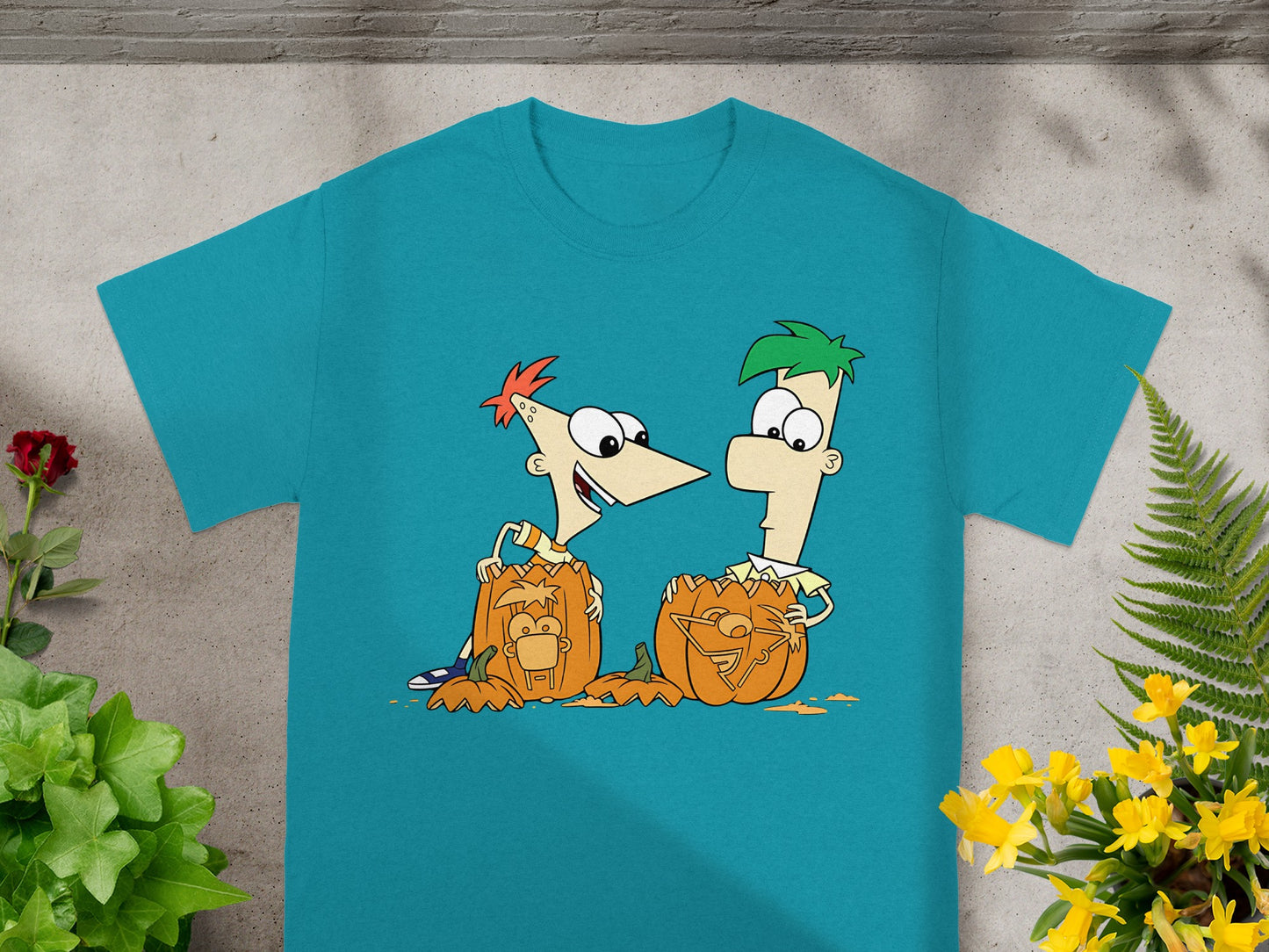 Phineas and Ferb characters with carved pumpkins on a teal t-shirt.