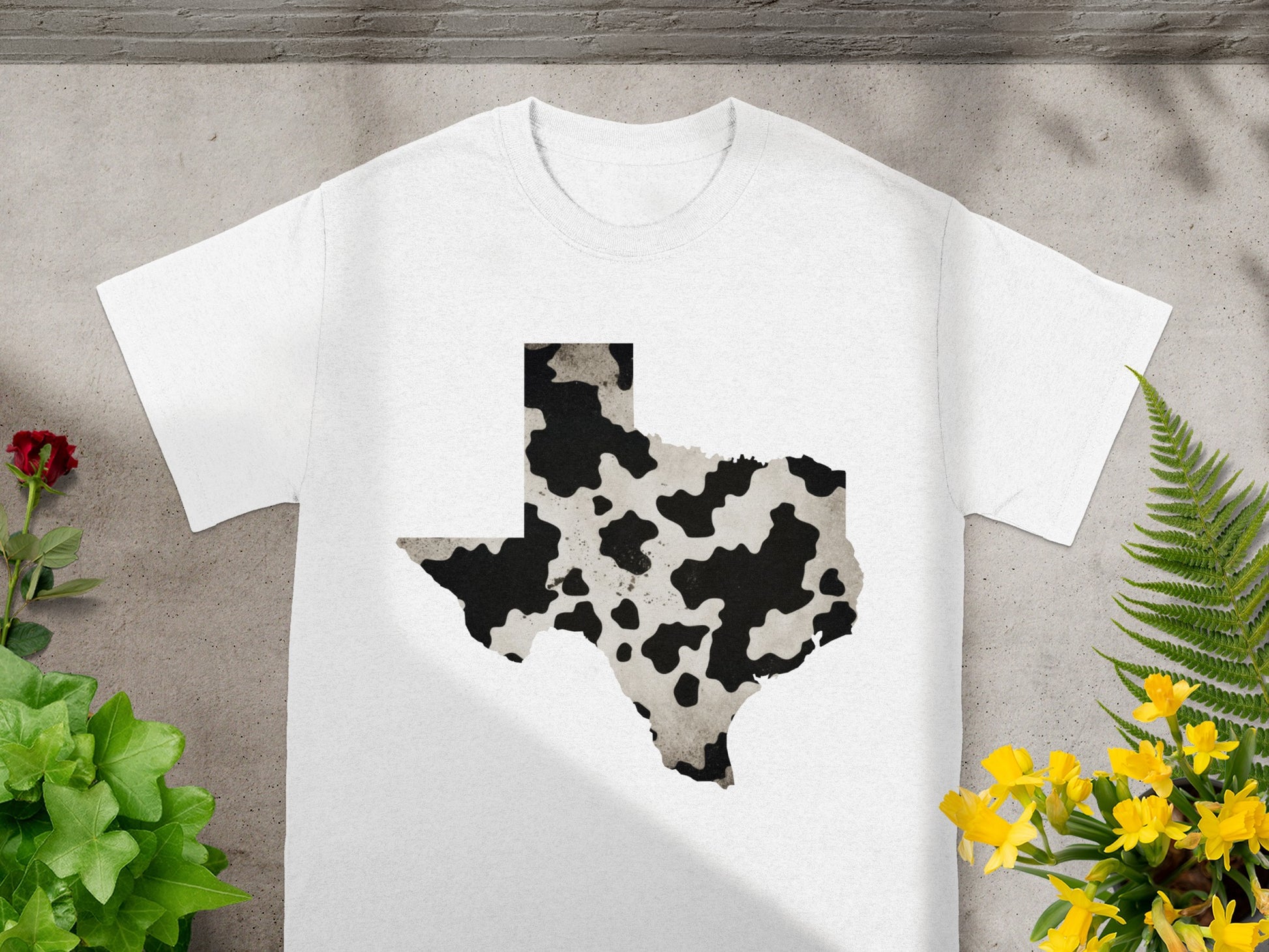 White t-shirt with Texas outline graphic in cow print pattern.