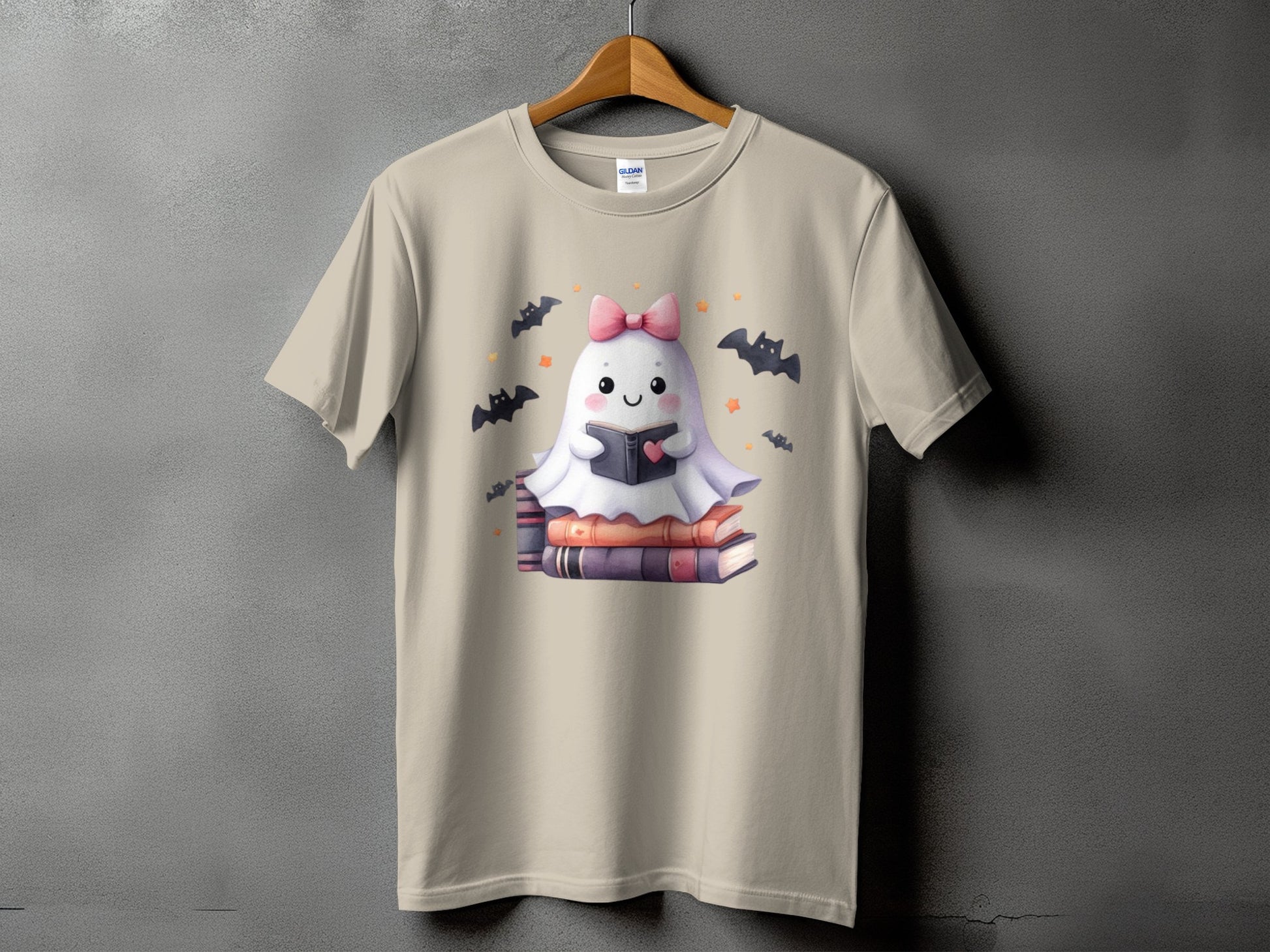 Tan t-shirt with a cute ghost reading a book, surrounded by bats.