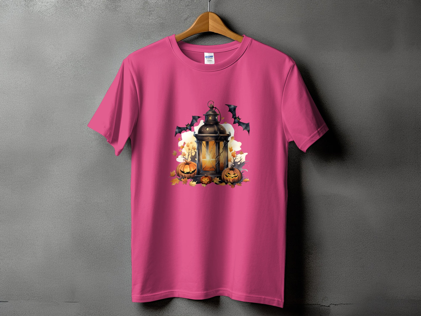 Pink t-shirt with Halloween lantern, pumpkins, bats, and fall leaves graphic.