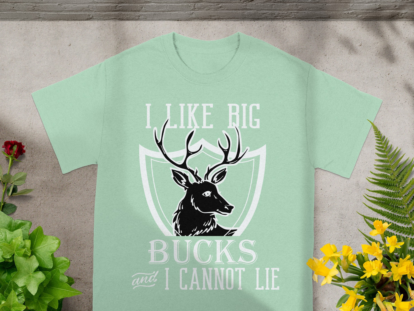 Light green t-shirt with deer graphic and text "I LIKE BIG BUCKS and I CANNOT LIE".