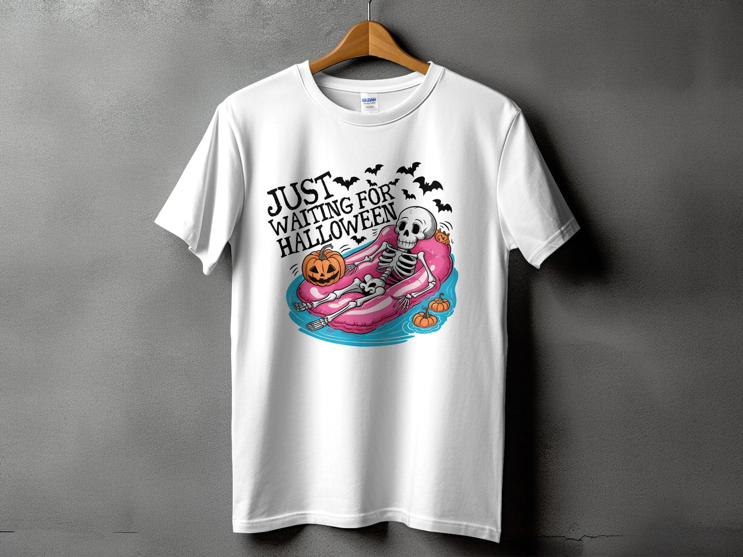 White t-shirt with skeleton floating on pool float, text "JUST WAITING FOR HALLOWEEN".