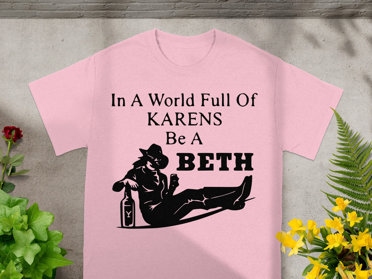 Pink t-shirt with "In A World Full Of KARENS Be A BETH" text and silhouette.