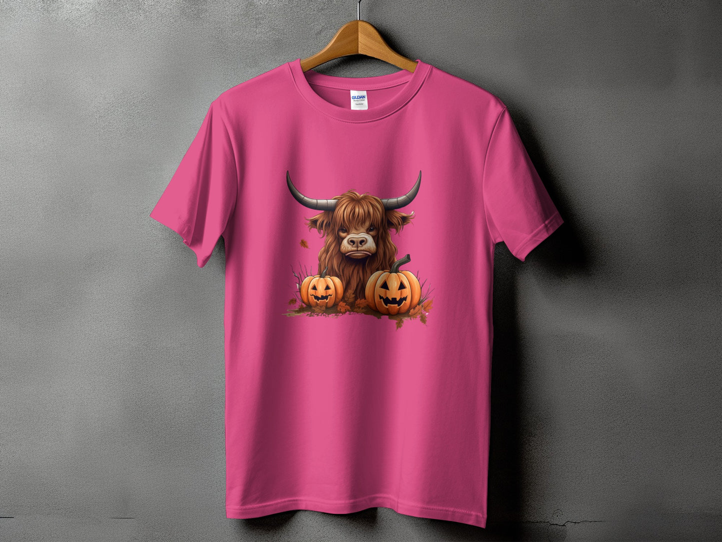 Highland cow with pumpkins graphic on a pink t-shirt.