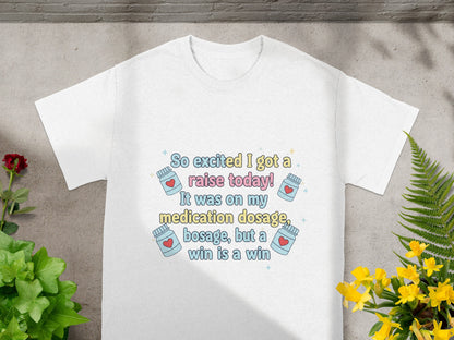 White t-shirt with text "So excited I got a raise today! It was on my medication dosage, but a win is a win."
