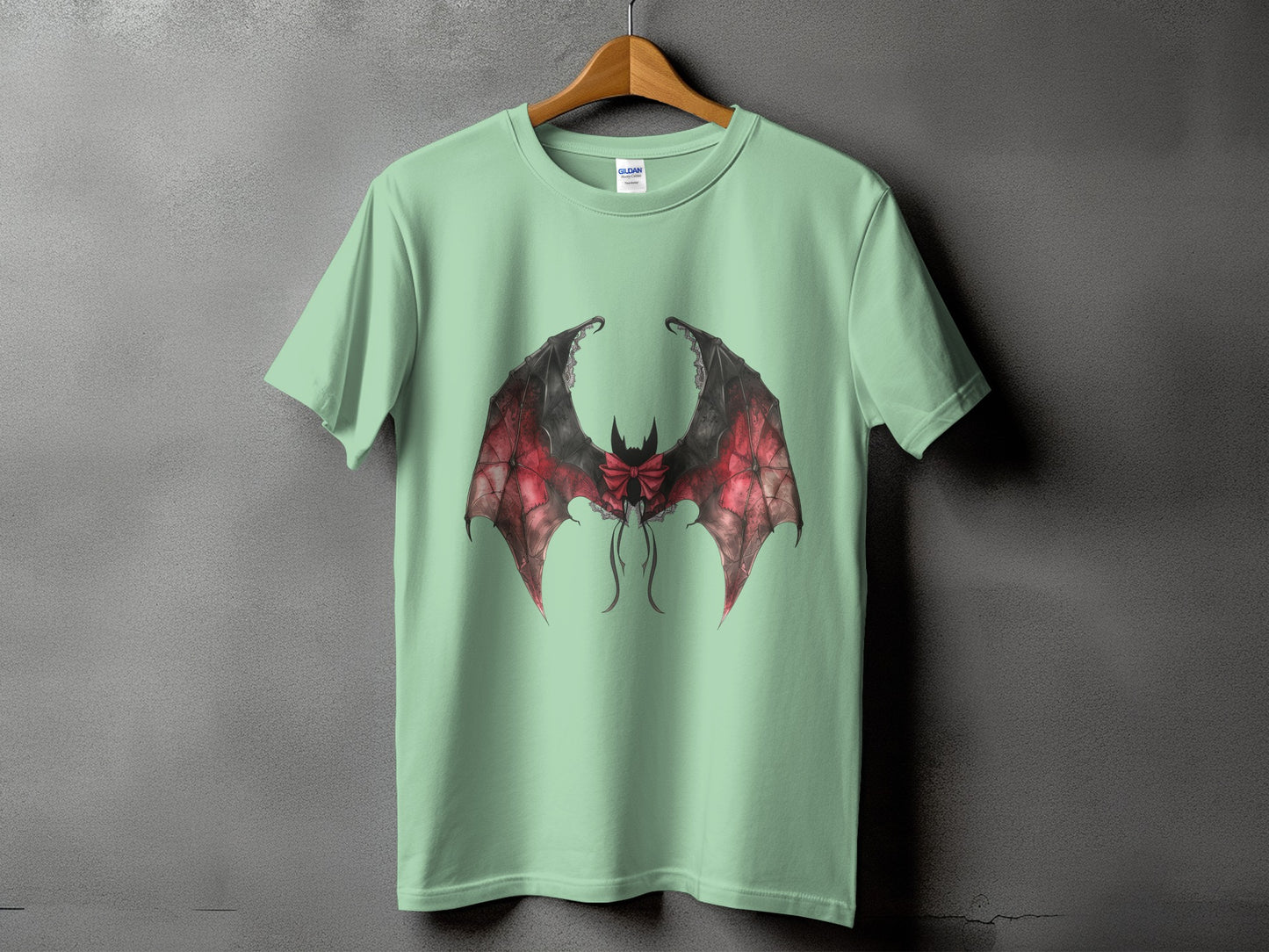 Light green t-shirt with a black and red bat wings graphic with a bow.