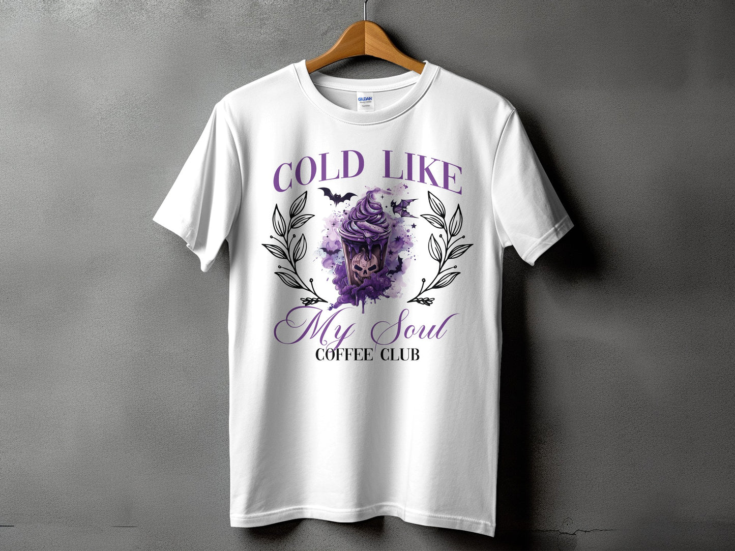 White t-shirt with purple text "COLD LIKE MY SOUL COFFEE CLUB" and a spooky dessert graphic.