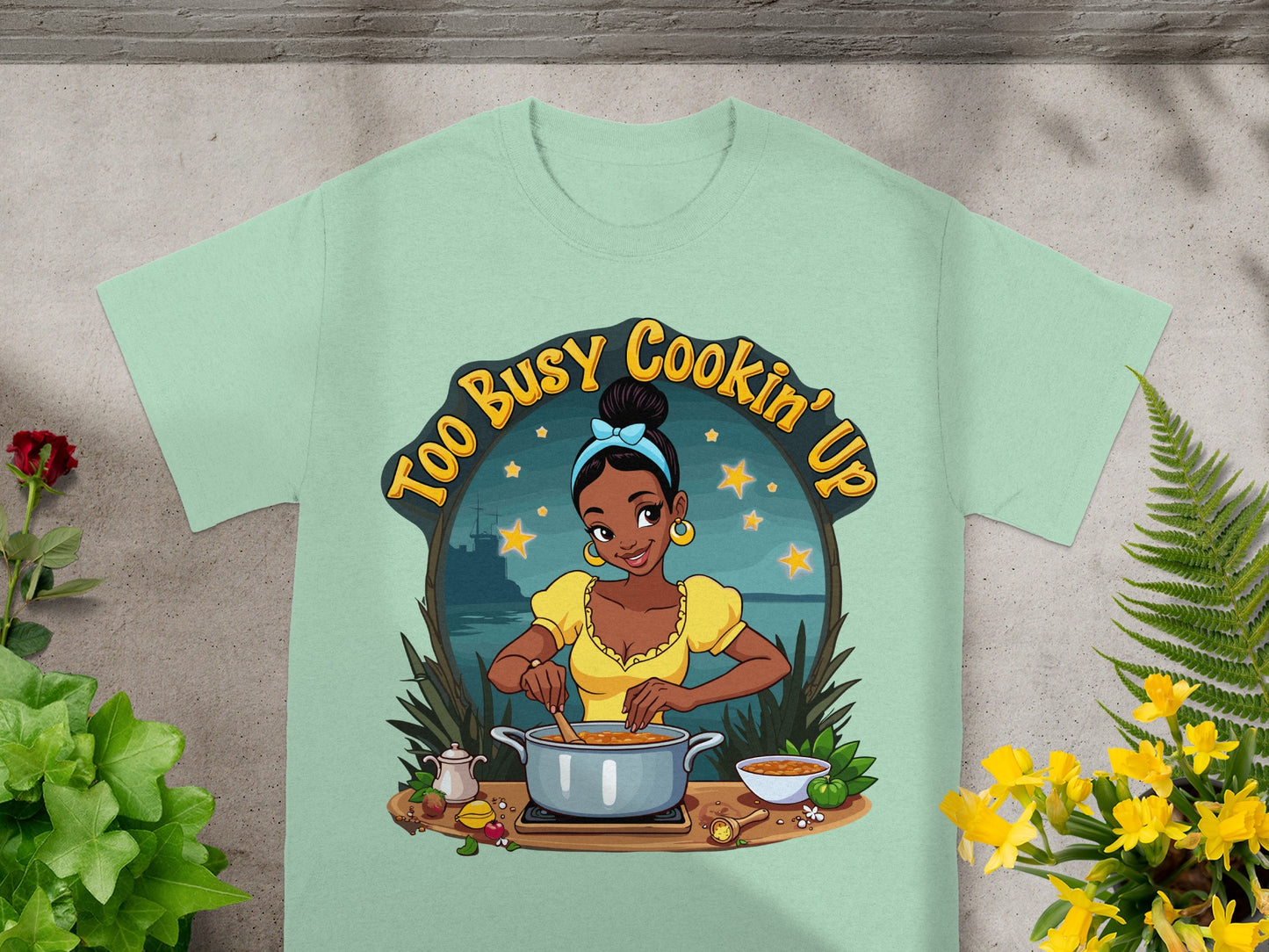 T-shirt graphic of a woman cooking, with text "Too Busy Cookin' Up".