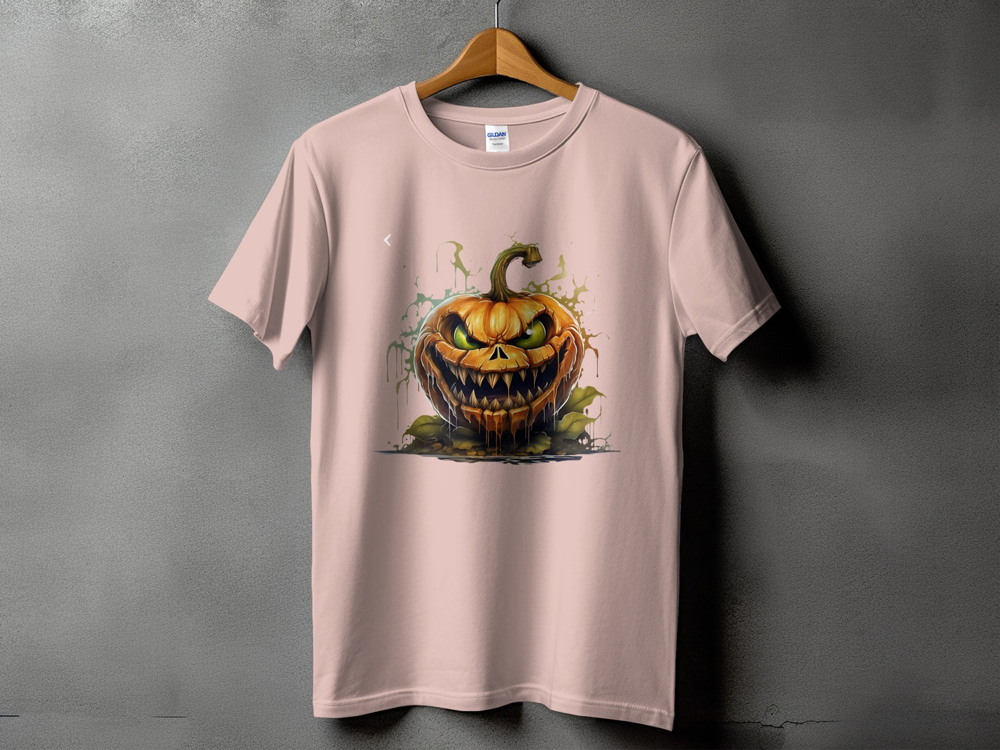 Pink t-shirt featuring a detailed illustration of a scary, grinning jack-o'-lantern with green eyes.