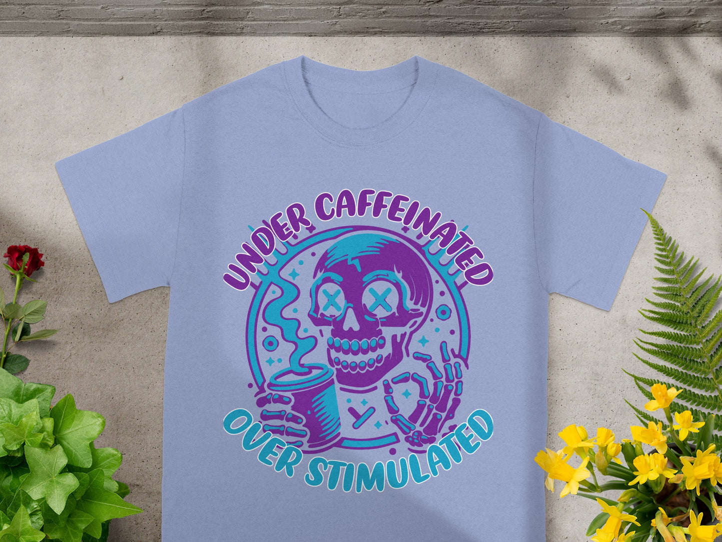 T-shirt with graphic of a skeleton holding a coffee cup, text reads "Under Caffeinated Over Stimulated".
