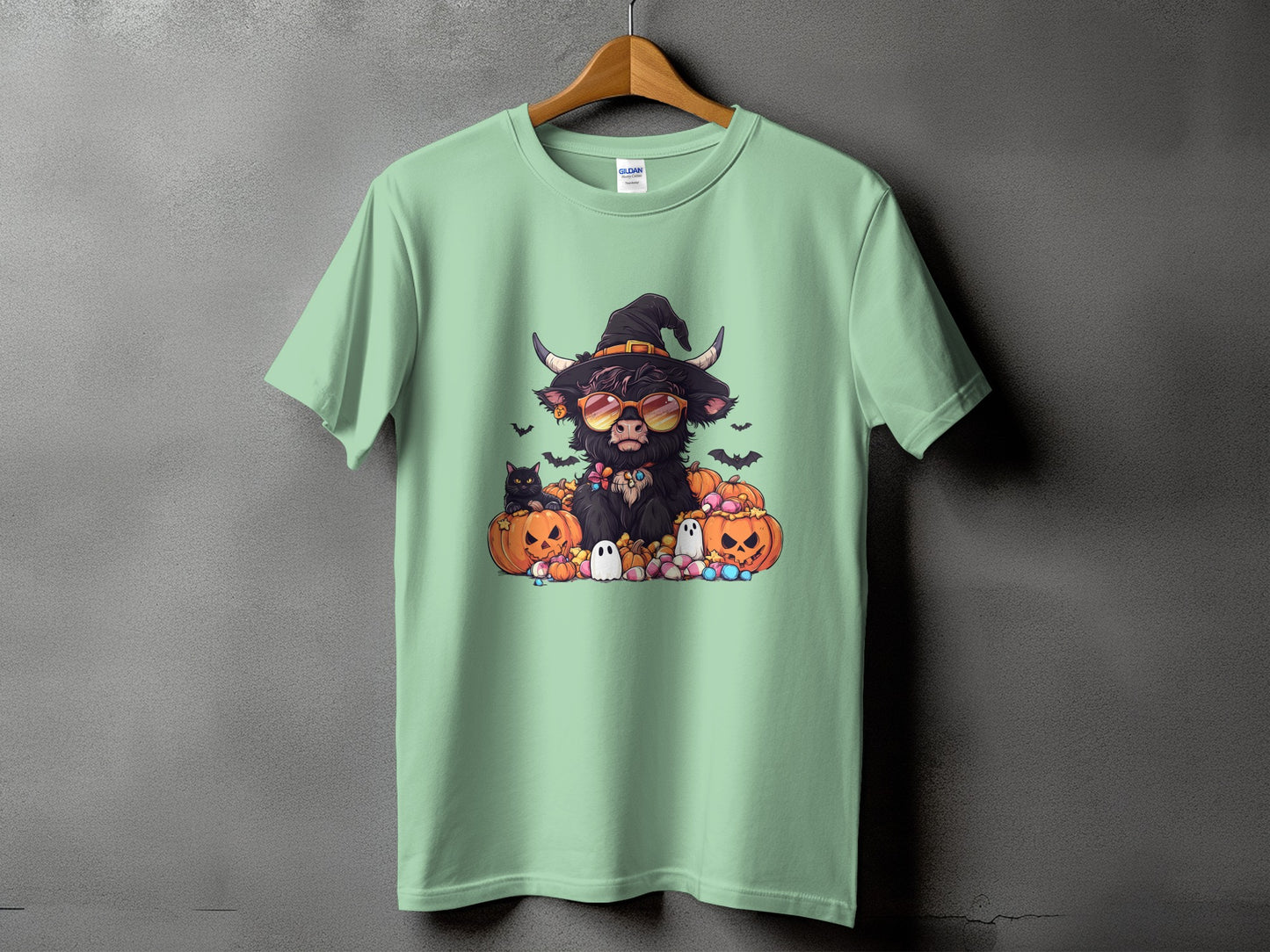 Green t-shirt with Halloween graphic of a cow wearing a witch hat and sunglasses.