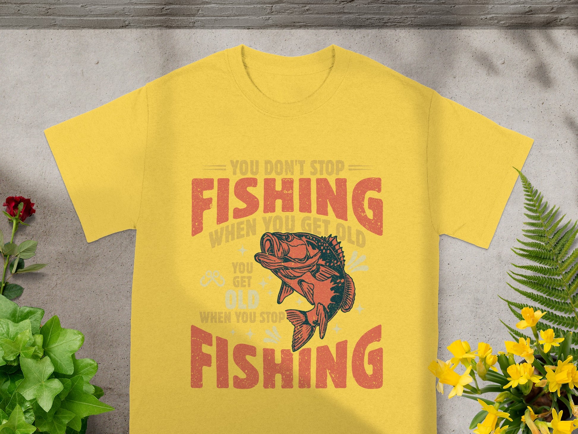 Yellow t-shirt with "You Don't Stop Fishing When You Get Old" text and fish graphic.
