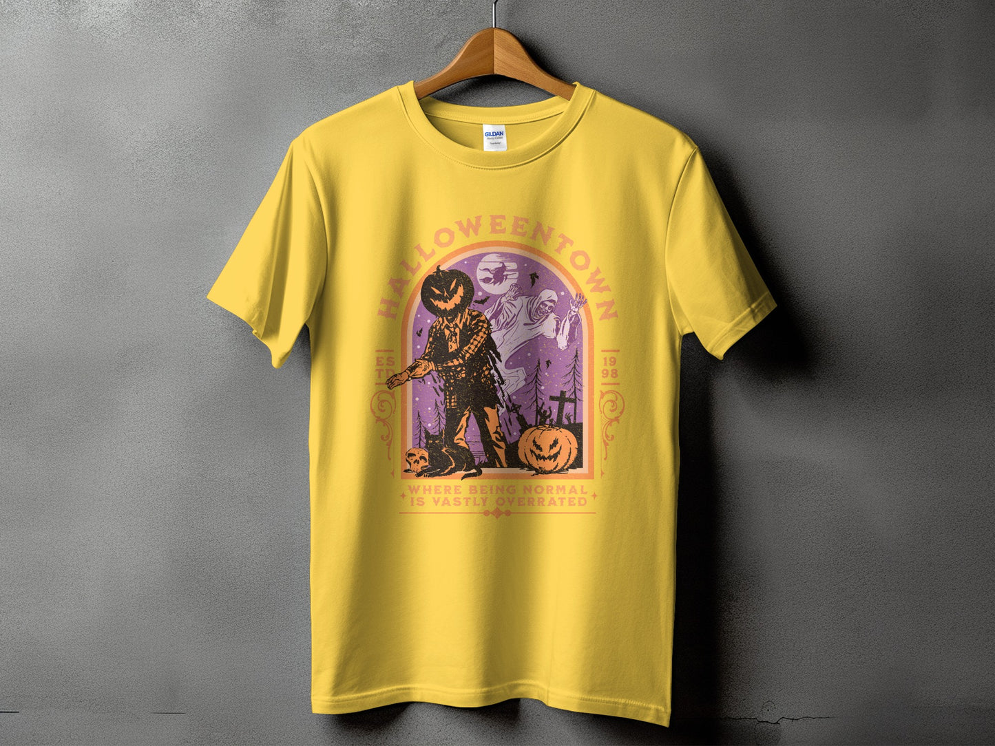 Yellow t-shirt with Halloween town graphic featuring a scarecrow, ghost, and pumpkins.