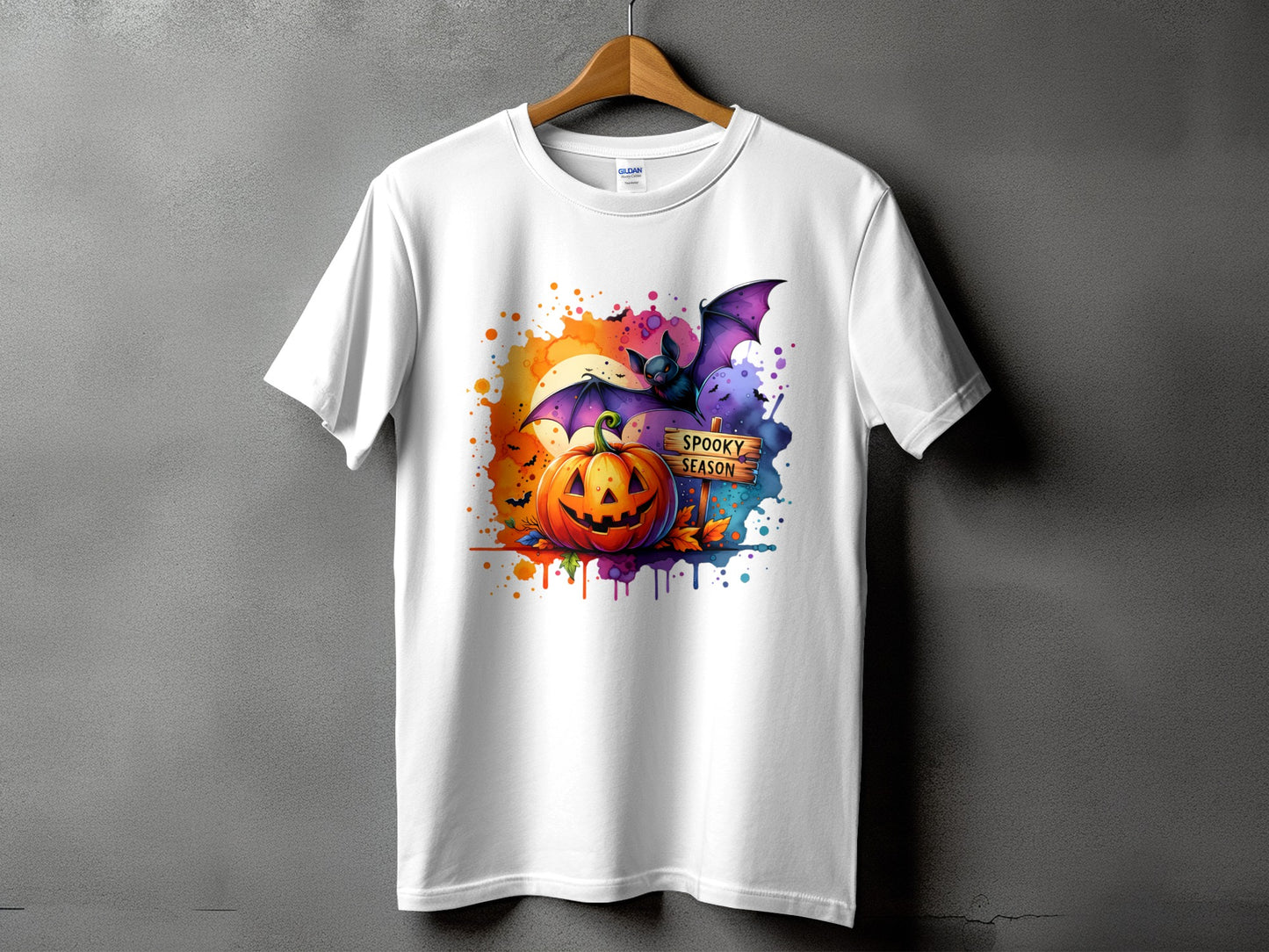 White t-shirt with a Halloween graphic featuring a pumpkin, bat, and "Spooky Season" sign.