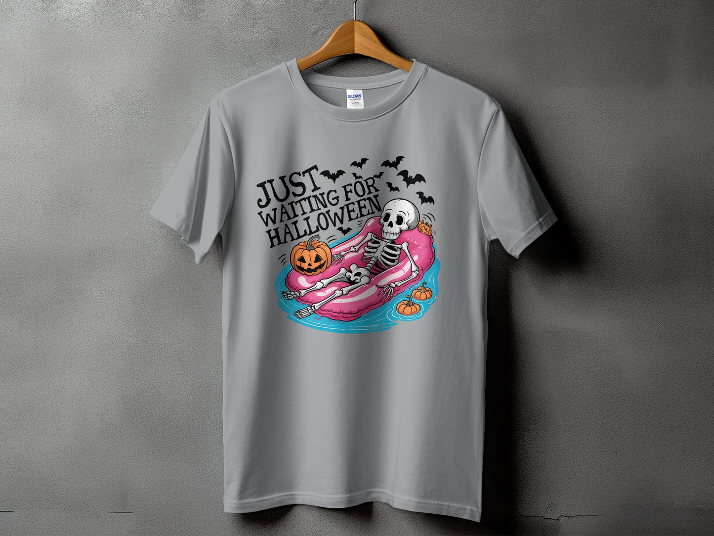 Grey t-shirt with skeleton on pool float and text "JUST WAITING FOR HALLOWEEN."
