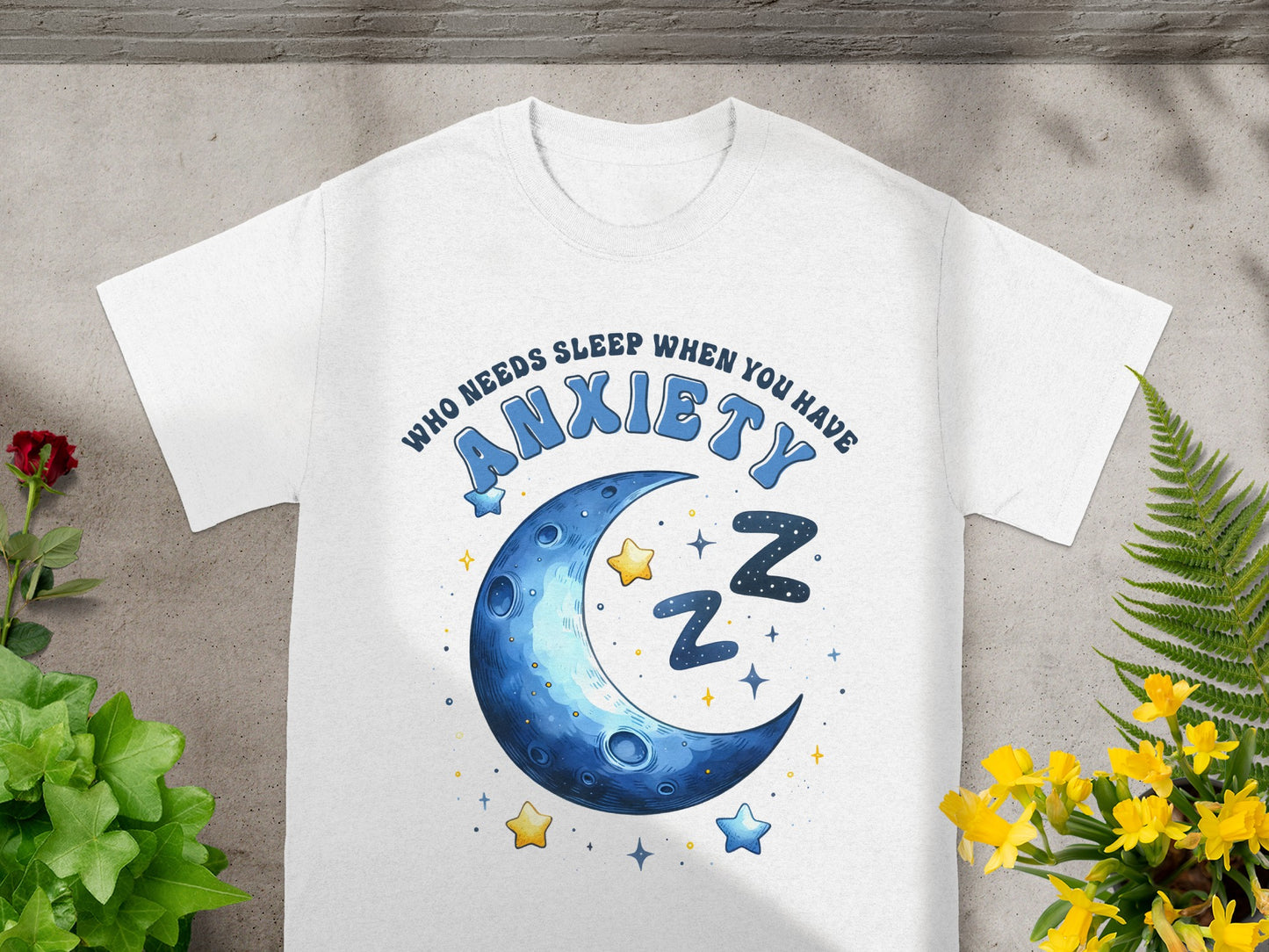 White t-shirt with blue text "WHO NEEDS SLEEP WHEN YOU HAVE ANXIETY" and crescent moon graphic.