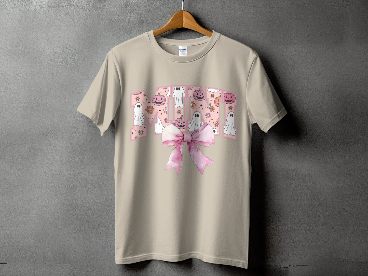 Beige t-shirt with pink Halloween graphic featuring ghosts, pumpkins, and a bow.